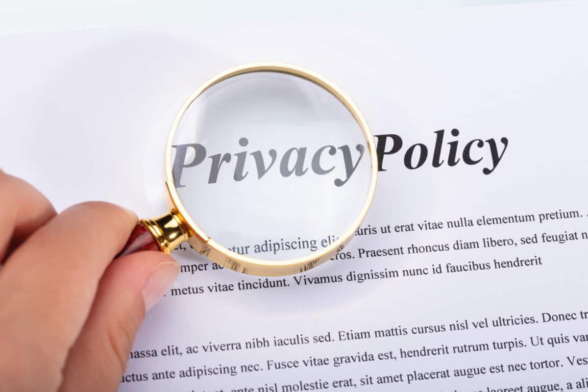 Close-up Of A Woman's Hand Holding Magnifying Glass Over Privacy Policy Form