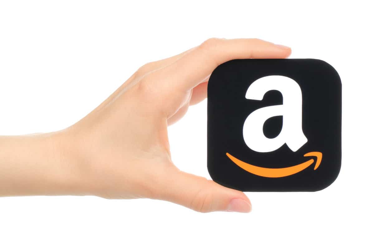 Hand holds Amazon icon printed on paper.