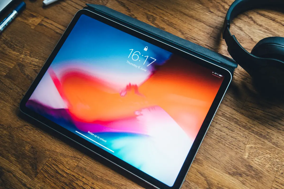 Paris, France - June 7, 2019: View from above of new iPAd Pro tablet featuring home lock screen and current hour - wooden table and Beats Studio by Dr Dre headphones