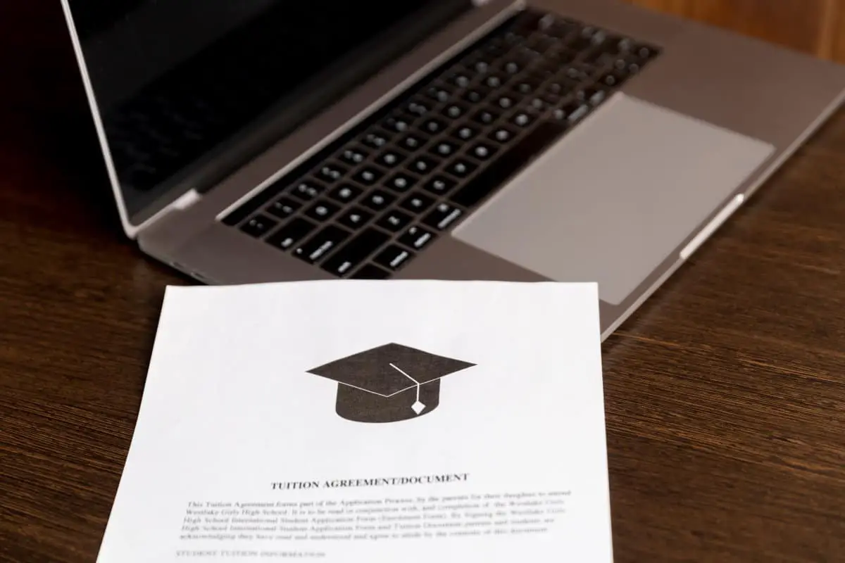 Papers (college or university document with graduation cap on it) laying on top of a laptop.